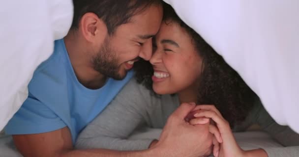 Happy couple, love and trust between man and woman sharing a bond, laugh and commitment while lying close in bed at home. Closeup of interracial man and woman spending free time on weekend together. - Footage, Video