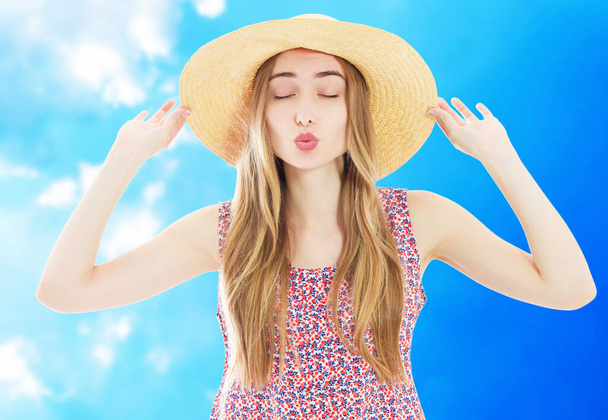 Модный портрет красивая женщина в соломенной шляпе летом посылает воздушный поцелуй на свежем голубом фоне - Фото, изображение