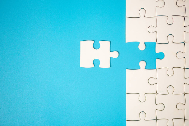 White part of jigsaw puzzle pieces on blue background. concepts of problem solving, business success, teamwork, Team playing jigsaw game incomplete, Texture photo with copy space for text - Foto, Imagem