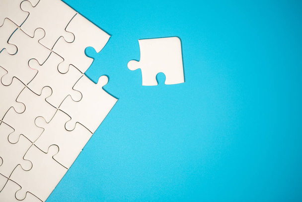 White part of jigsaw puzzle pieces on blue background. concepts of problem solving, business success, teamwork, Team playing jigsaw game incomplete, Texture photo with copy space for text - Valokuva, kuva