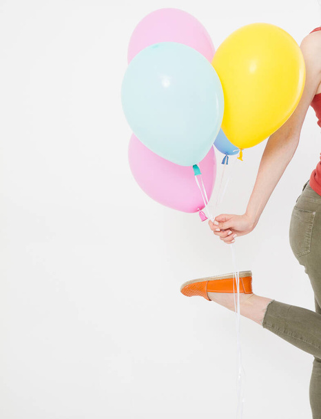 Beyaz arka planda izole edilmiş renkli balonlarla koşan genç bir kız. Boşluğu kopyala - Fotoğraf, Görsel