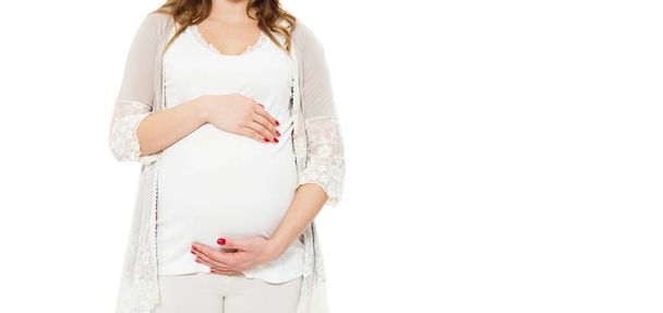 Pregnant woman holds hands on belly on a white background. Pregnancy, maternity, preparation and expectation concept. Close-up, copy space, indoors. Beautiful tender mood photo of pregnancy. - Foto, Imagen