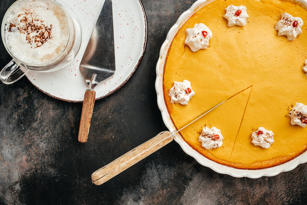Traditional autumn dish Spicy pumpkin pie with whipped cream latte with cinnamon on black stone table. Healthy food trend. top view. - Foto, Imagen
