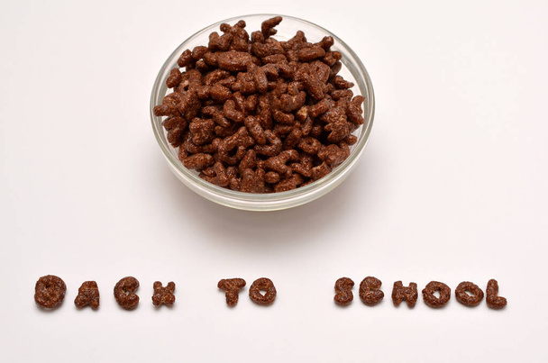płatki czekolady w misce i tekst z powrotem do szkoły z liter alfabetu na białym tle - Zdjęcie, obraz
