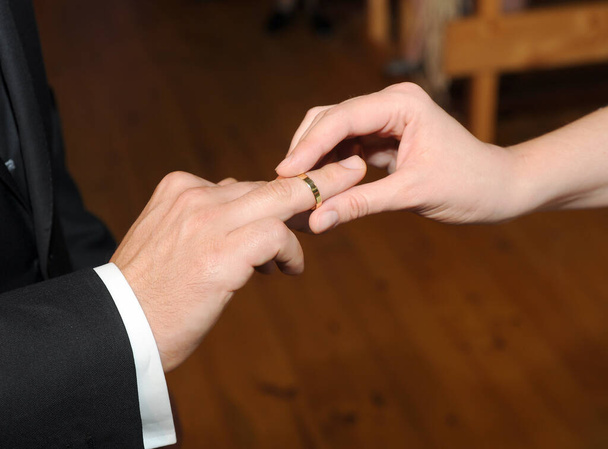 Veduta di un anello d'oro che una donna sta mettendo sul suo futuro marito durante il loro matrimonio. - Foto, immagini