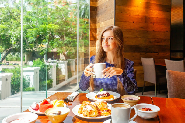 Attractive woman on breakfast in hotel restaurant. Businesswoman on meeting dine in modern cafe, drinking coffee. Business lunch concept - Foto, afbeelding