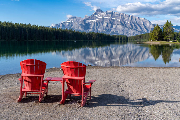 バンフ国立公園の海岸線に象徴的な赤い無声の椅子がある2つのジャック湖 - 写真・画像