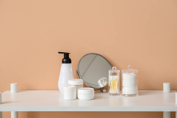 Miroir et différents accessoires de bain sur la table près du mur beige - Photo, image