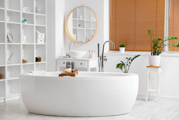 Интерьер стильной ванной комнаты с полками и комнатными растениями - Фото, изображение