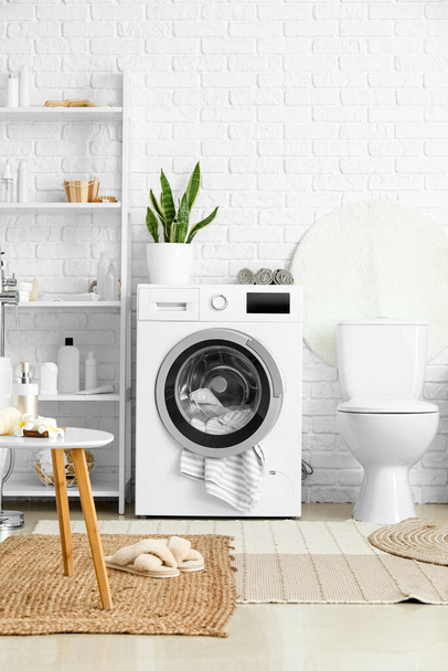 Modern çamaşır makinesi, klozet ve aksesuarlı raf ünitesi olan bir banyo. - Fotoğraf, Görsel