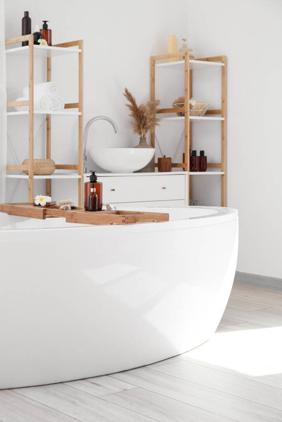 Сучасна ванна і полиця з банними аксесуарами в інтер'єрі ванної кімнати
 - Фото, зображення