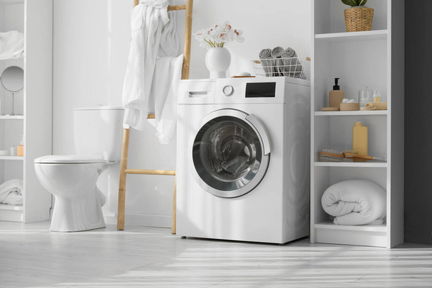 Moderna lavatrice e mensola con accessori bagno vicino alla parete bianca - Foto, immagini