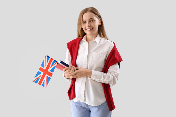 Молодая женщина с флагом Великобритании и книгами на светлом фоне - Фото, изображение