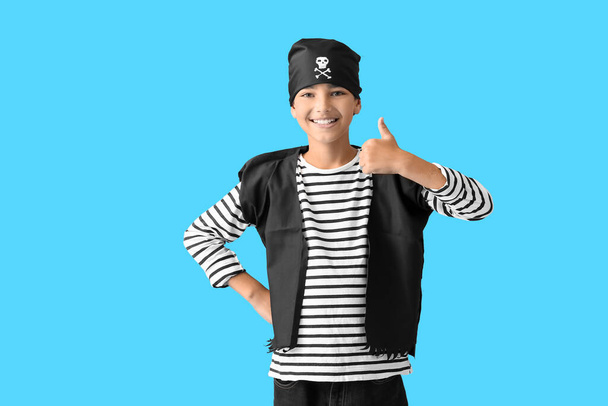 Menino vestido de pirata mostrando polegar para cima no fundo azul - Foto, Imagem