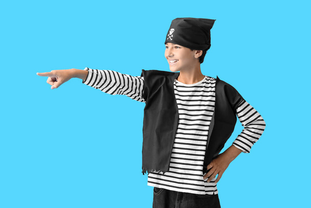 Niño vestido de pirata señalando algo sobre fondo azul - Foto, imagen