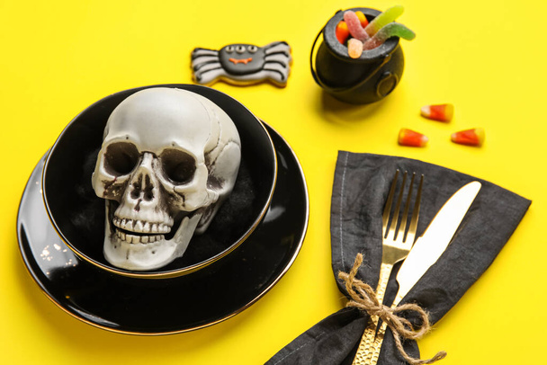 Nastavení stolu s lebkou a halloween dekor na žlutém pozadí, detailní záběr - Fotografie, Obrázek