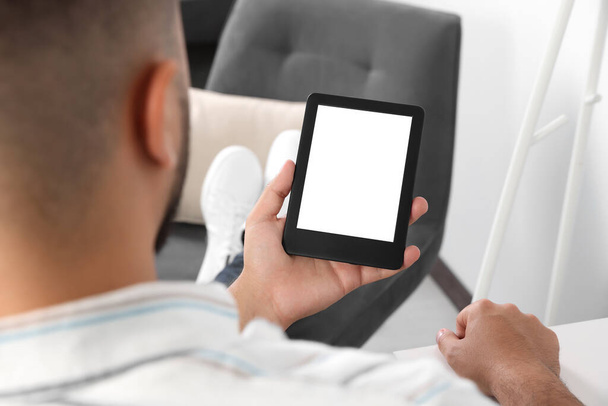 Man using e-book reader indoors, closeup view - Фото, изображение