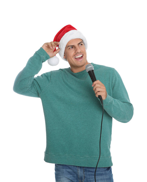 Emotional man in Santa Claus hat singing with microphone on white background. Christmas music - Foto, afbeelding