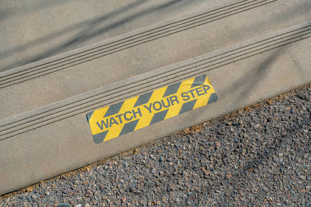 Colado ver o seu sinal de adesivo passo em um passo concreto em Tucson, Arizona. Vista de um sinal preto e amarelo em uma escada de dois passos de cima. - Foto, Imagem