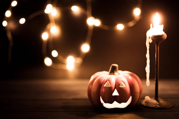 Halloween pumpkin wallpaper with candle and string lights bokeh in the background. Toned vintage colors, copy space. - Photo, Image
