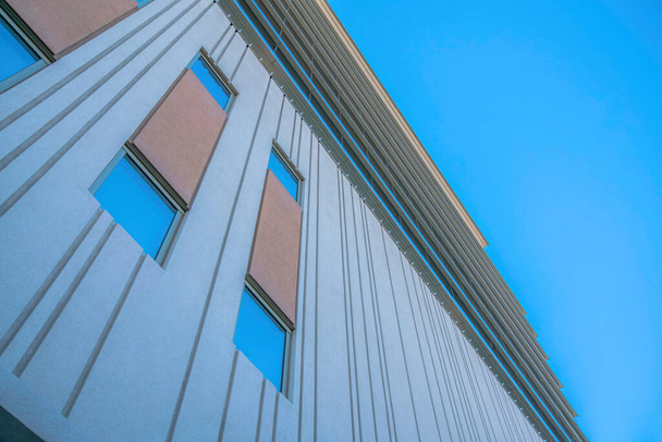 Vista de bajo ángulo de un edificio con paredes pintadas de gris en el centro de Tucson, Arizona. Edificio de poca altura con ventanas altas sobre el fondo azul claro del cielo. - Foto, Imagen