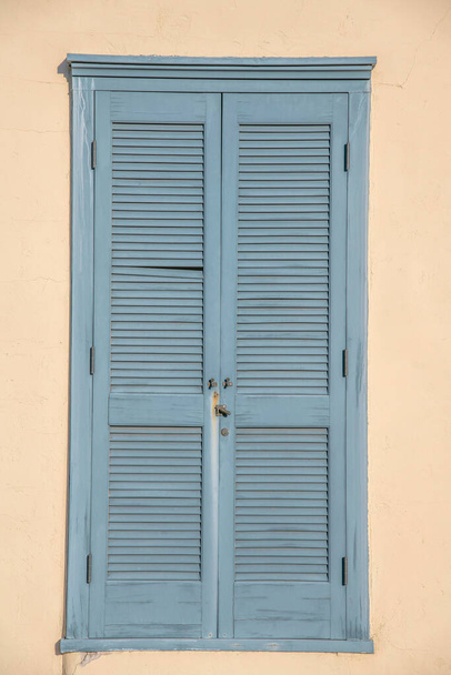 Hellblaue Holzfenstertür gegen die beige Wand in der Innenstadt von Tucson, Arizona. Alte lackierte Holztür mit seitlichen Scharnieren. - Foto, Bild