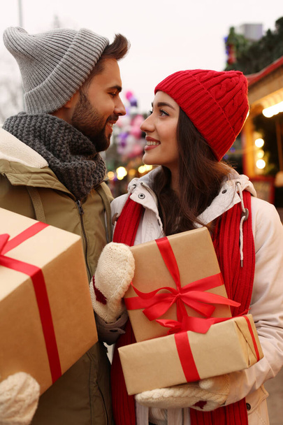 Lovely couple with Christmas presents at winter fair - Photo, image