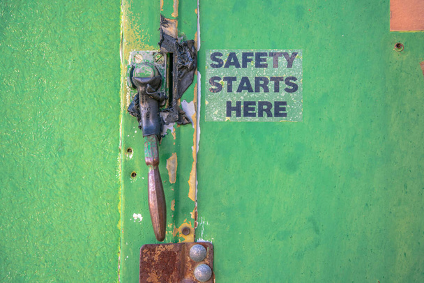 Mount Lemmon, Arizona- Metal handle with Safety Starts Here sign on the side. Rusty green metal surface of a door with door handle. - Photo, Image