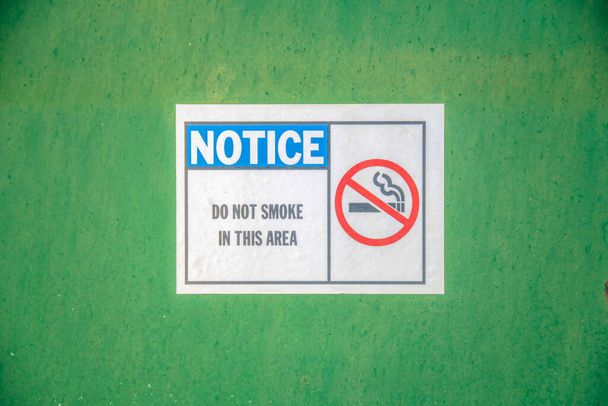 Mount Lemmon, Arizona- Notice with Do Not Smoke in This Area with No Smoking Symbol on the sign. Close up of a signage pasted on a green wall. - Photo, Image