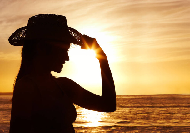 Kobieta w słomkowym kapeluszu przeciwko pięknemu morzu o zachodzie słońca. Pasująca kobieta w słomkowym kapeluszu przeciwko pięknemu morzu o zachodzie słońca - Zdjęcie, obraz
