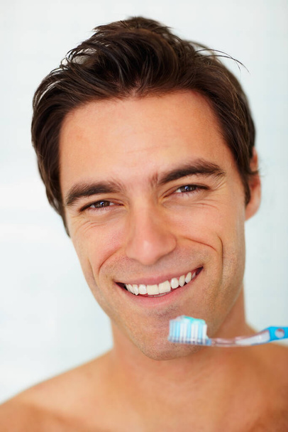 Detailní záběr šťastného mladíka, který si právě čistí zuby. Osobní hygiena - Detailní záběr usmívajícího se mladíka, který se chystá vyčistit si zuby - Fotografie, Obrázek
