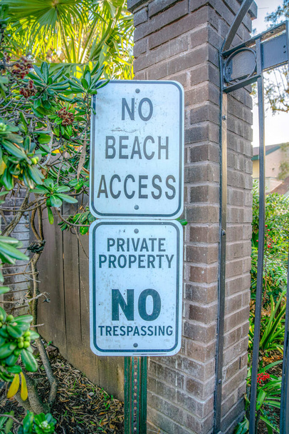 La Jolla, California-Dwa znaki na słupie bez dostępu do plaży, własności prywatnej i zakaz wtargnięcia. Znaki na słupku na zewnątrz bramy z cegły słupka i roślin w pobliżu ściany. - Zdjęcie, obraz