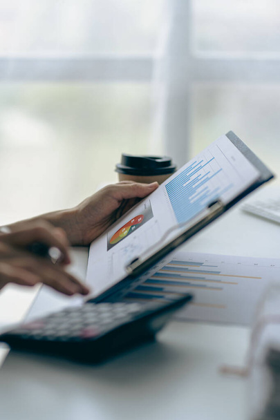 üzleti ember kezében toll és pite chart dokumentum mutatja a vállalati pénzügyi adatokat ül egy privát irodában egy laptop elemzi a pénzügyi adatokat chart formában. pénzügyi koncepció - Fotó, kép