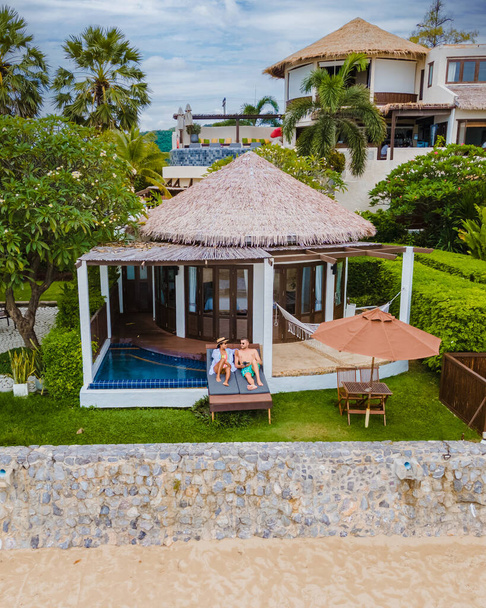 Couple in luxury villa enjoying in the plunge pool looking out over ocean and beach on a luxury vacation. Men and women on vacation relaxing at front of their pool villa - Photo, Image