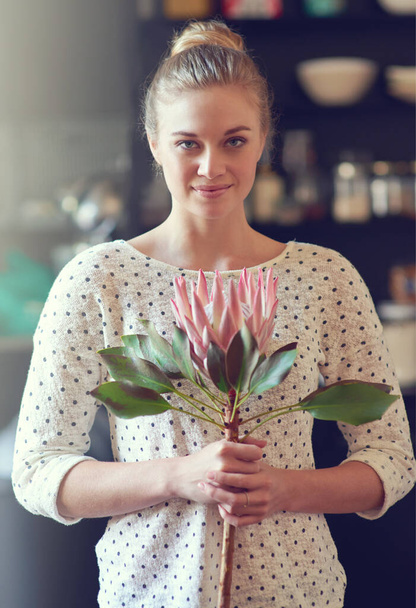 The beauty of fynbos. Portrait of a beautiful young woman standing in her kitchen holding a protea flower - Foto, afbeelding