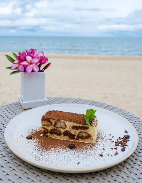Italian dessert tiramisu on a beach in Thailand. Vanilla pudding and coffee - Photo, Image