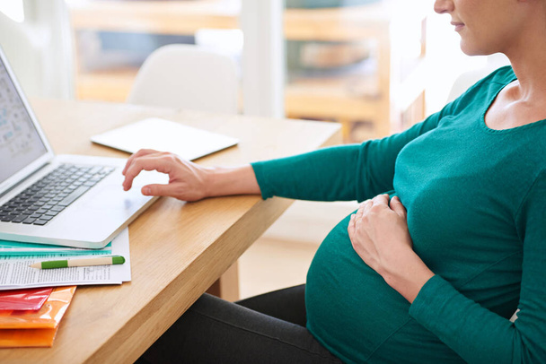 Recueillir des conseils parentaux en ligne. une femme enceinte utilisant son ordinateur portable à la maison - Photo, image