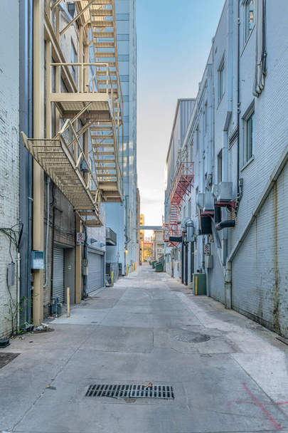 Остин, Техас бетонный переулок между соседними жилыми зданиями. По обеим сторонам переулка есть здания с аварийной лестницей и мусорными баками.. - Фото, изображение