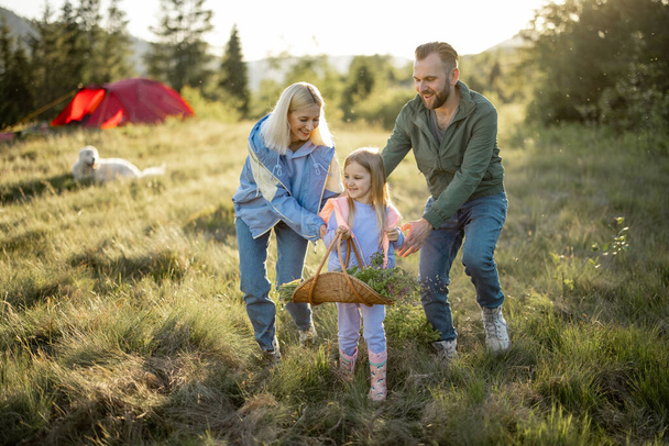 Young caucasian couple with little girl have fun while travel in the mountains. Happy family spending summer vacation at campsite - Photo, Image