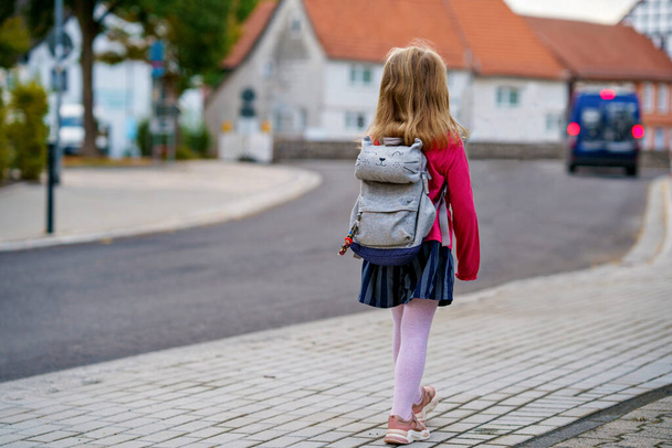 Cute little girl przedszkola o drodze do szkoły Zdrowe szczęśliwe dziecko spaceru do przedszkola i przedszkola. Uśmiechnięte dziecko z plecakiem na ulicy, na świeżym powietrzu. Wracamy do szkoły. - Zdjęcie, obraz