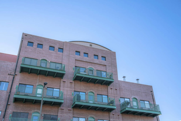 Феникс, Аризона - Промышленный жилой дом с балконами под низким углом зрения. Внешний вид квартиры с красными кирпичными стенами и балконами с арочными зелеными дверями. - Фото, изображение