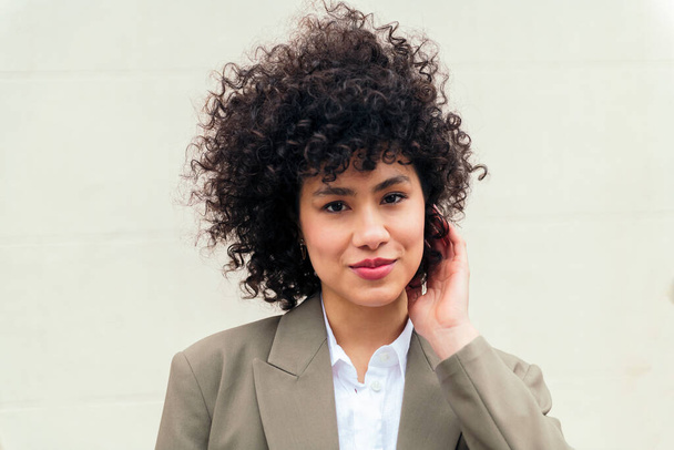 portrait of a stylish business woman smiling happy touching her curly hair, concept of successful entrepreneur and youth, copy space for text - Foto, immagini