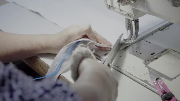 Ompelija työpajassa ompelee tuotteen, joka on valmistettu valkoisesta aidosta nahasta, jossa on valkoiset langat ompelukoneessa - Materiaali, video