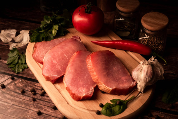 Sliced smoked meat on a wooden table with addition of fresh herbs and aromatic spices. Natural product from organic farm, produced by traditional methods - Foto, immagini