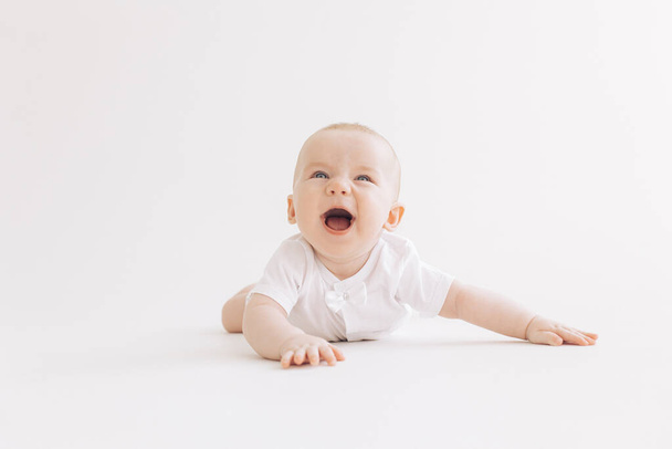 幸せな赤ちゃんの男の子は陽気に白い背景に横たわって笑う. - 写真・画像