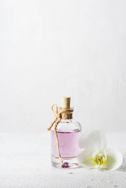 Rose essential oil in glass bottle and orchid flower on white background. - Fotoğraf, Görsel