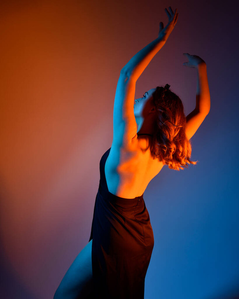 Close up retrato da bela mulher modelo vestindo vestido preto elegante, posando contra um fundo de estúdio com fantasia inspirada gestos de braço, iluminação criativa multi colorido. - Foto, Imagem