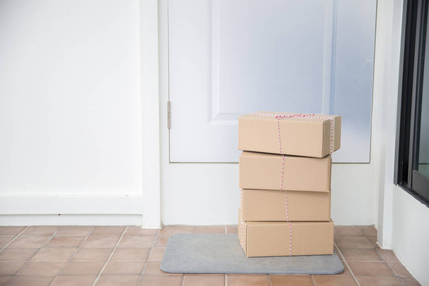 Cardboard parcel box near door on floor. Online shopping, boxes delivered to your front door. Easy to steal when nobody is home. Parcel in cardboard box on doorstep. Delivery service - Foto, Imagen