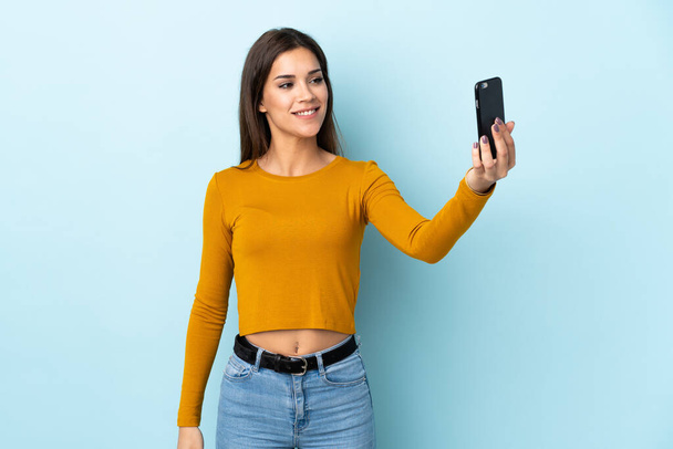 Young caucasian woman isolated on blue background making a selfie - Photo, Image