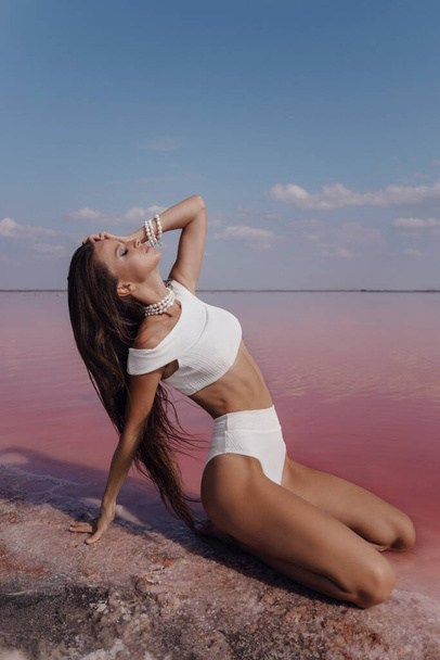 fashion outdoor photo photo of beautiful woman with dark hair in elegant swimmng suit posing on the pink salt lake - Zdjęcie, obraz